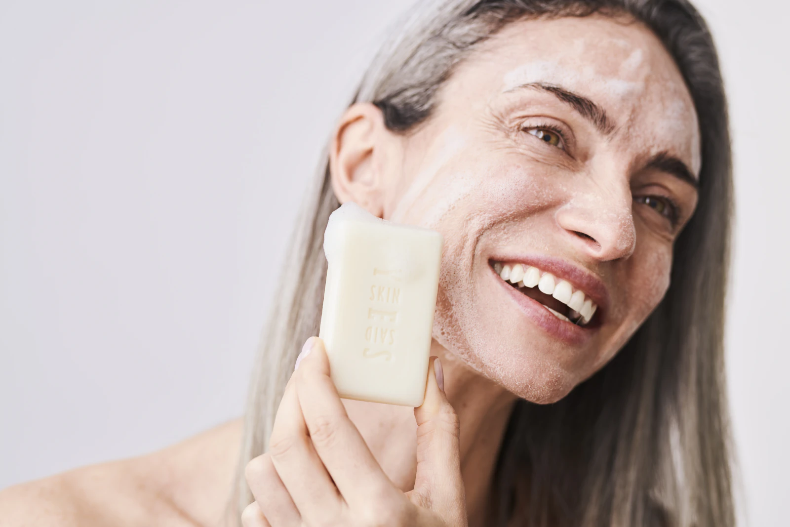 Smiling woman washing her face with a Skin Said Yes soap bar